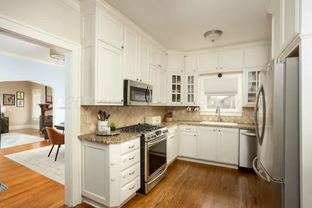 a kitchen with a sink cabinets stainless steel appliances and wooden floor