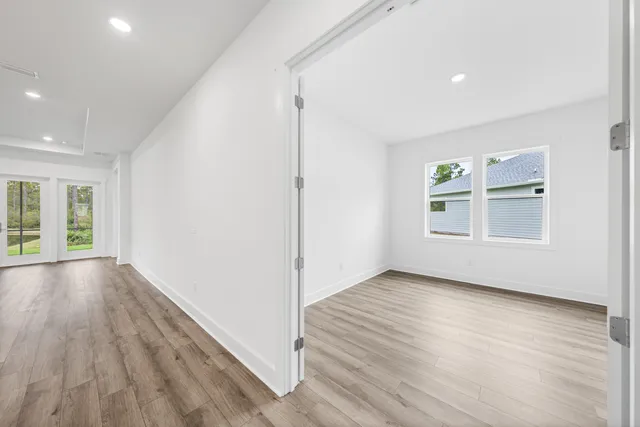 an empty room with wooden floor and windows