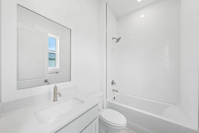 a bathroom with a bathtub shower sink vanity mirror and toilet