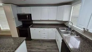 a kitchen with granite countertop a sink a stove and cabinets