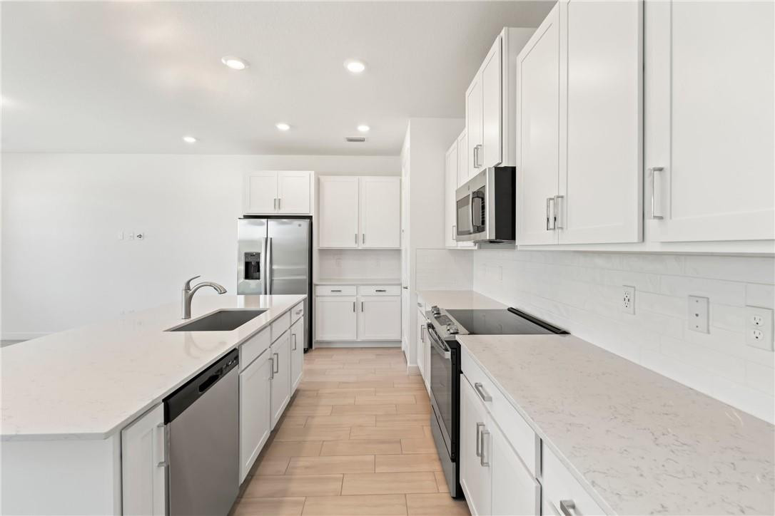 5653 Stradella Drive Boca Raton, FL 33433 - Photo 6 of 26 a kitchen with stainless steel appliances granite countertop a sink and dishwasher a stove top oven with wooden floor