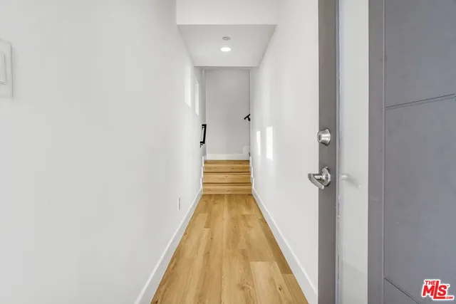 a view of a hallway with wooden floor and a bathroom