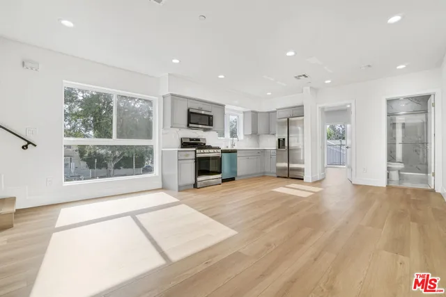 a view of kitchen with stainless steel appliances kitchen island wooden floor and living room view