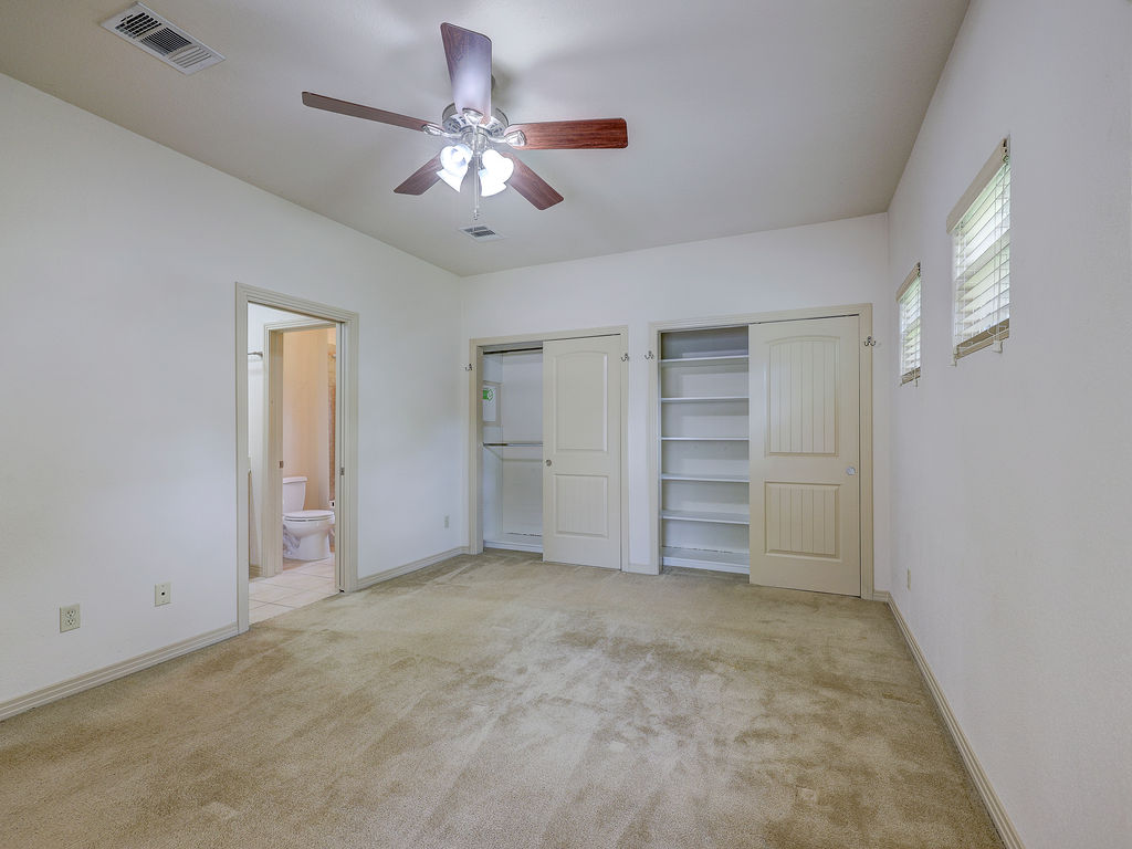 9707 Anderson Mill Road, Unit 22 Austin, TX 78750 - Photo 30 of 39 A comfortable bedroom features carpeted floors, built-in storage, and a private ensuite bathroom.