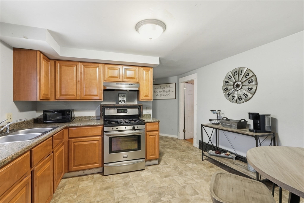 34 Savoy Avenue Springfield, MA 01104 - Photo 5 of 35 a kitchen with stainless steel appliances granite countertop a stove top oven a sink a dining table and chairs with wooden floor