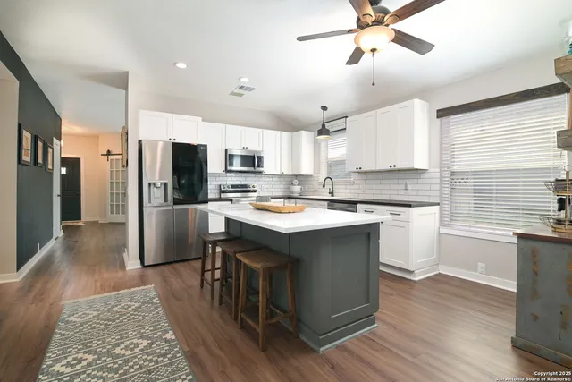 a kitchen with kitchen island a sink appliances a counter space and a window