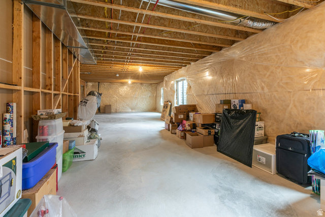 1228 North Providence Way Tooele, UT 84074 - Photo 21 of 28 Unfinished basement space featuring exposed wooden joists, concrete flooring, framed wall sections, and windows providing natural light