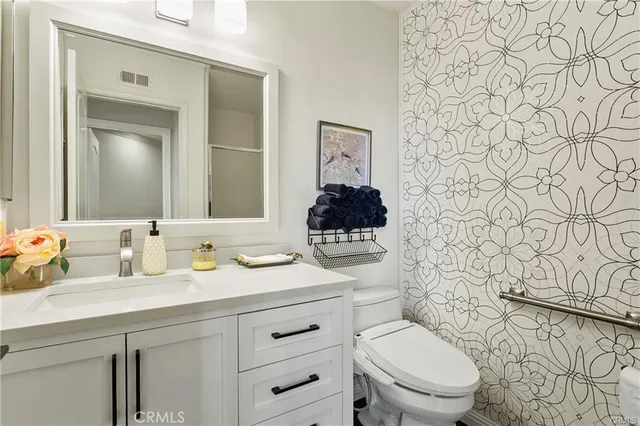 a bathroom with a granite countertop toilet sink and mirror