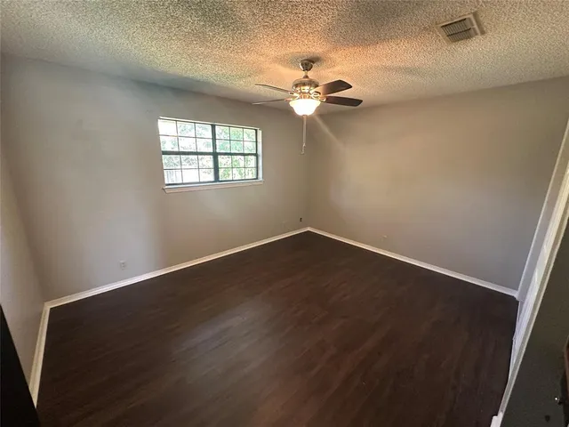 an empty room with wooden floor chandelier fan and windows