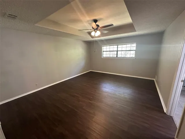 an empty room with wooden floor chandelier fan and windows