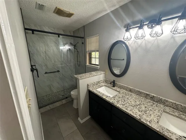 a bathroom with a granite countertop sink mirror vanity and toilet