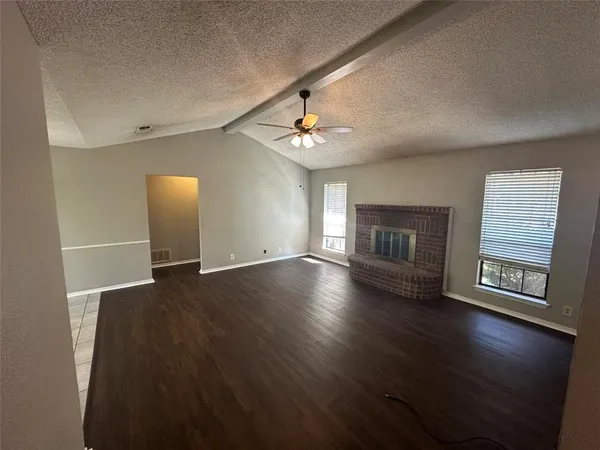 an empty room with windows and fireplace