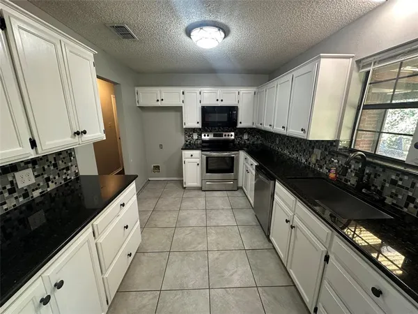 a kitchen with granite countertop a stove sink and cabinets