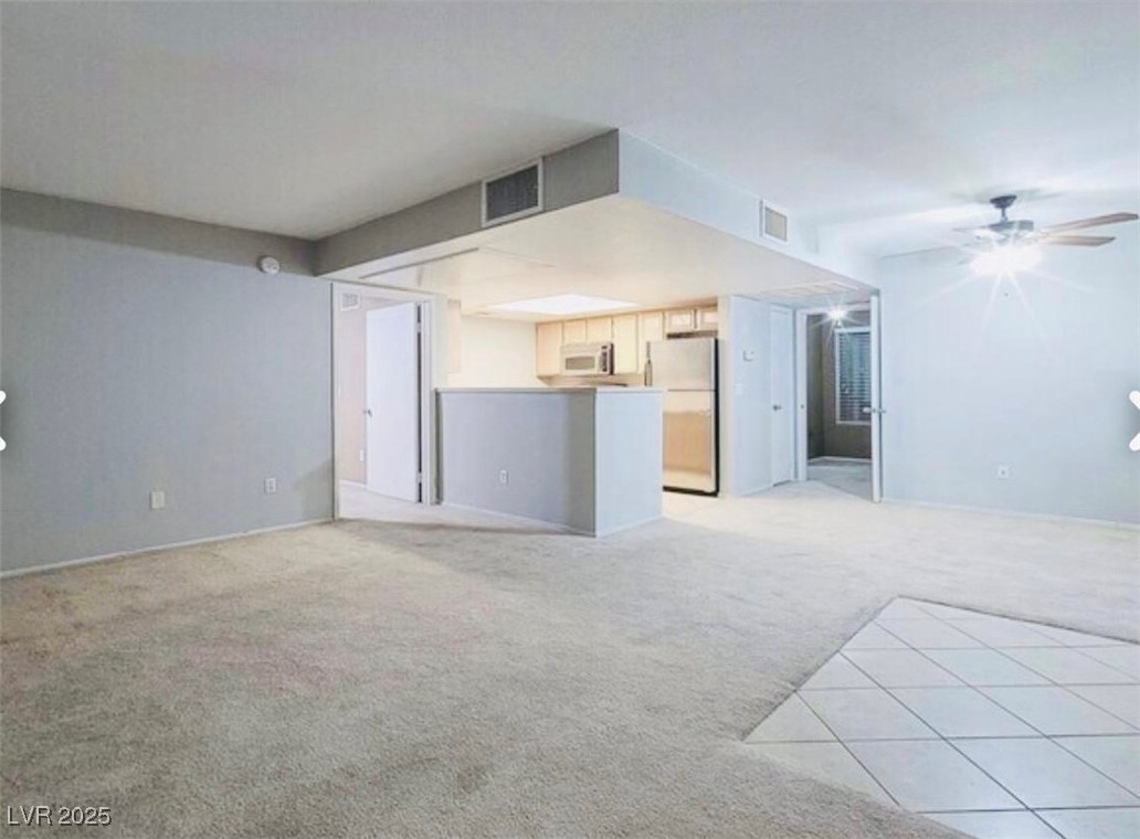 Unfurnished living room featuring a ceiling fan and light carpet