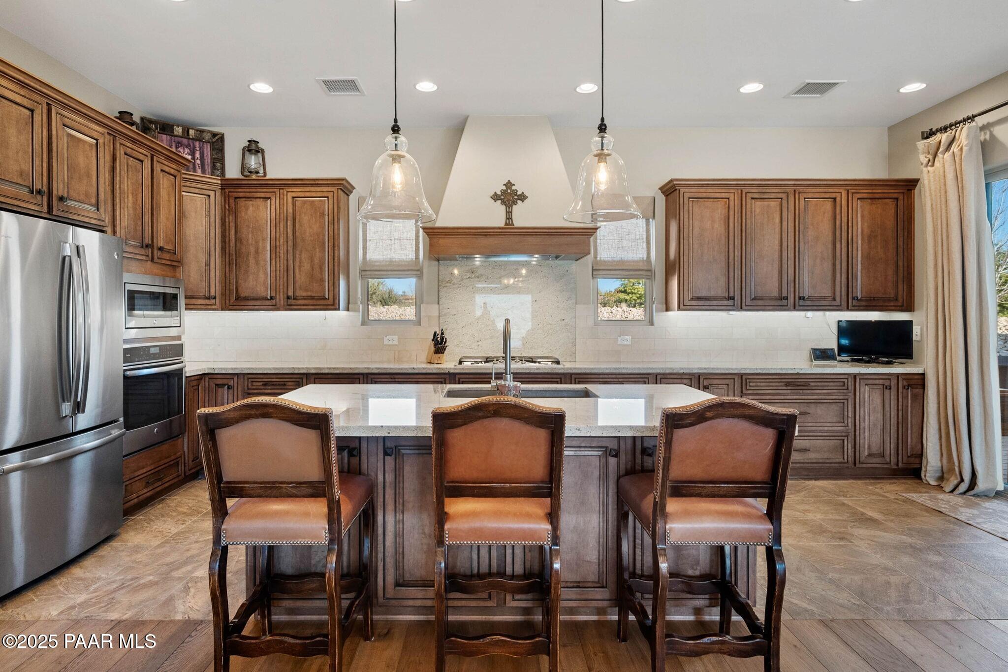 9309 North Callahan Road Prescott, AZ 86305 - Photo 13 of 55 a kitchen with granite countertop a table chairs microwave and refrigerator