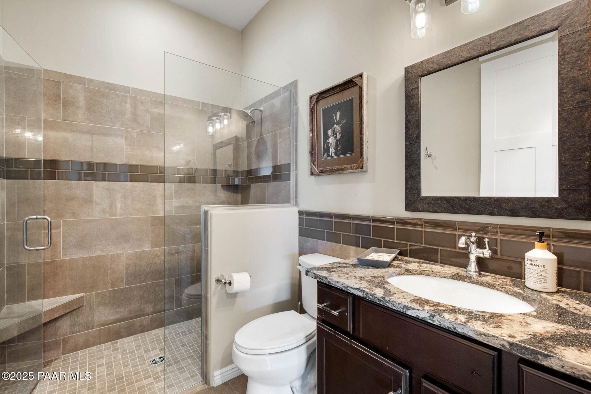 9309 North Callahan Road Prescott, AZ 86305 - Photo 24 of 55 a bathroom with a granite countertop sink a toilet and shower