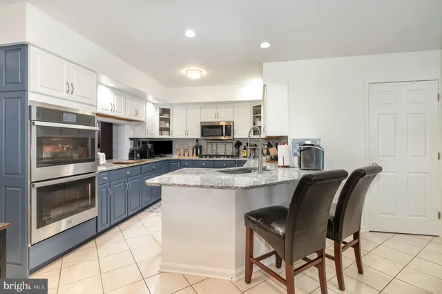 a kitchen with stainless steel appliances granite countertop a stove top oven a sink a dining table and chairs