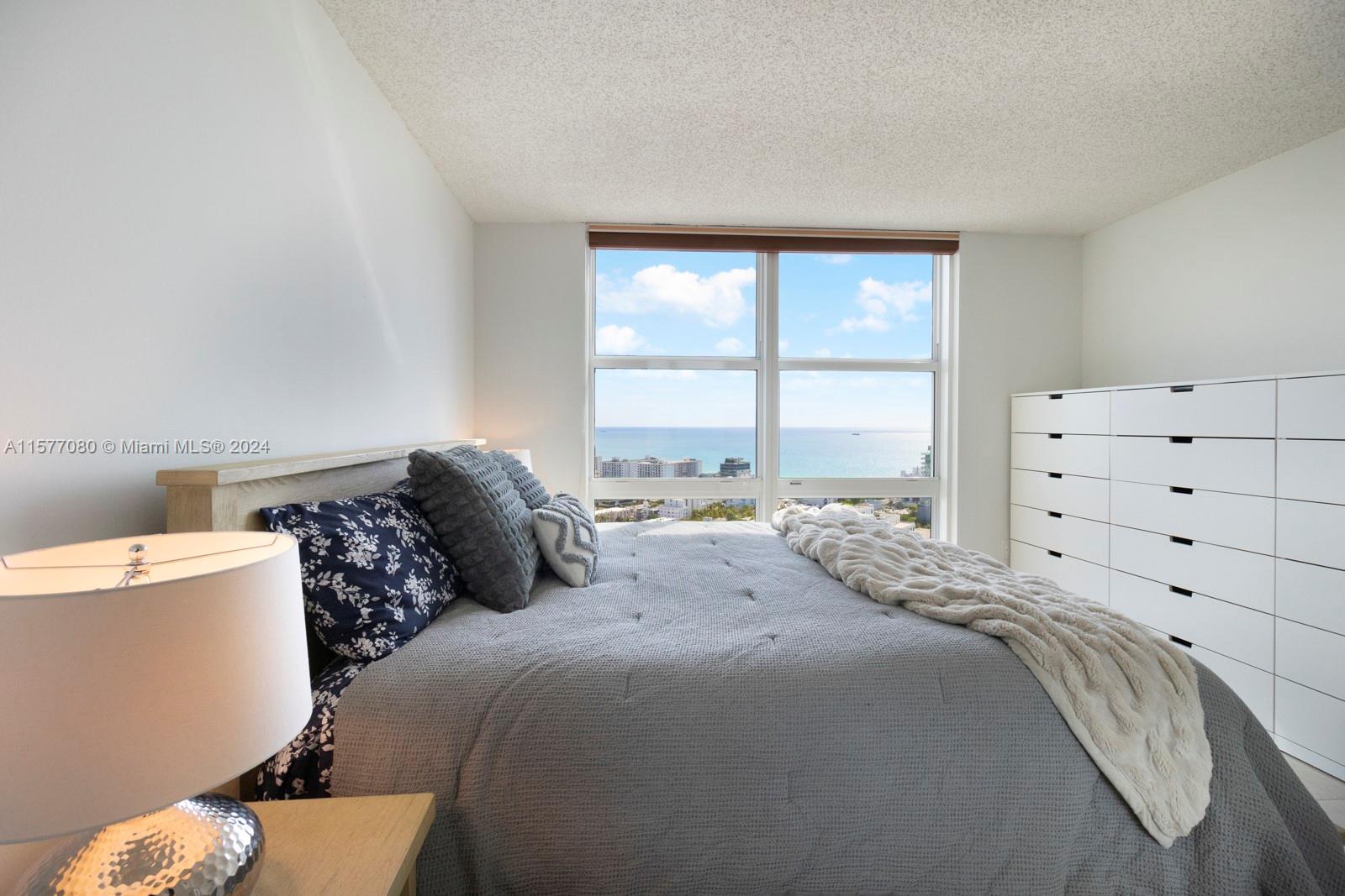 90 Alton Road, Unit 2907 Miami Beach, FL 33139 - Photo 12 of 18 a large bed sitting in a bedroom next to a window