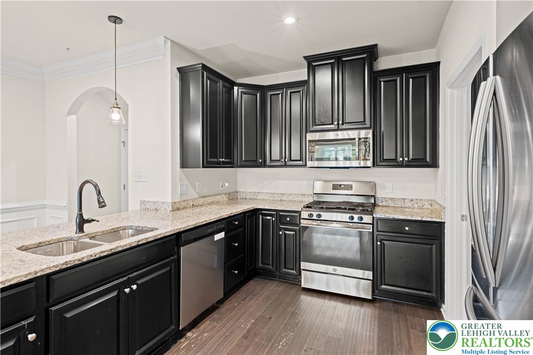 A well-appointed kitchen showcasing dark cabinetry, luminous granite countertops, and modern stainless steel appliances.