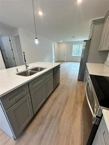 a large kitchen with a sink and wooden floor