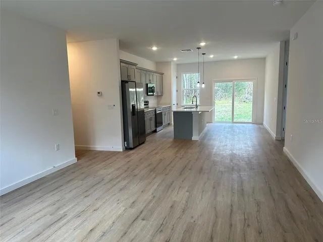a view of a kitchen with a fridge and wooden floor