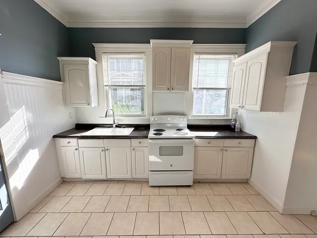 a white cabinets a sink a window and a refrigerator
