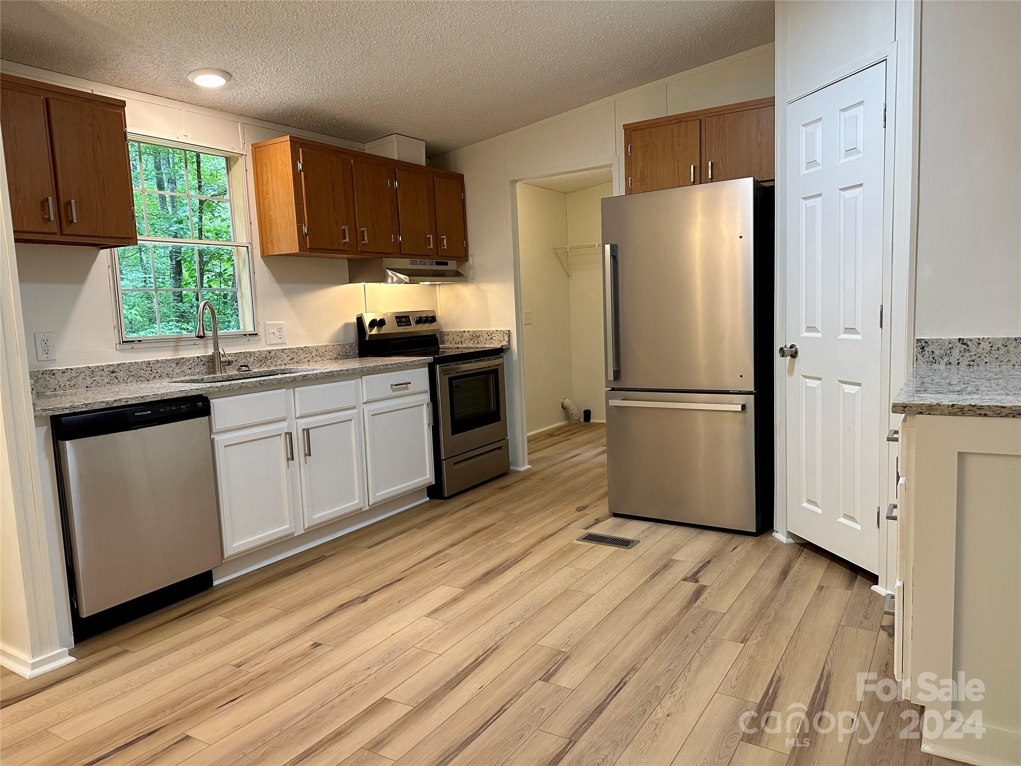 a kitchen with a refrigerator wooden floor a window and a sink