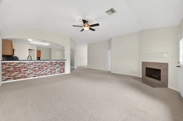 a view of a livingroom with a fireplace a ceiling fan and window