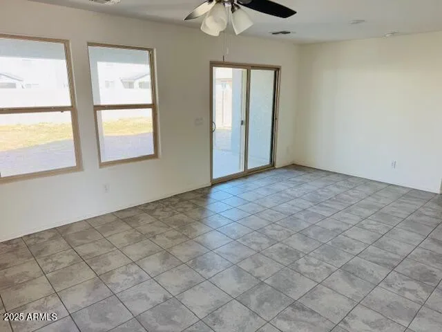 an empty room with windows and chandelier fan