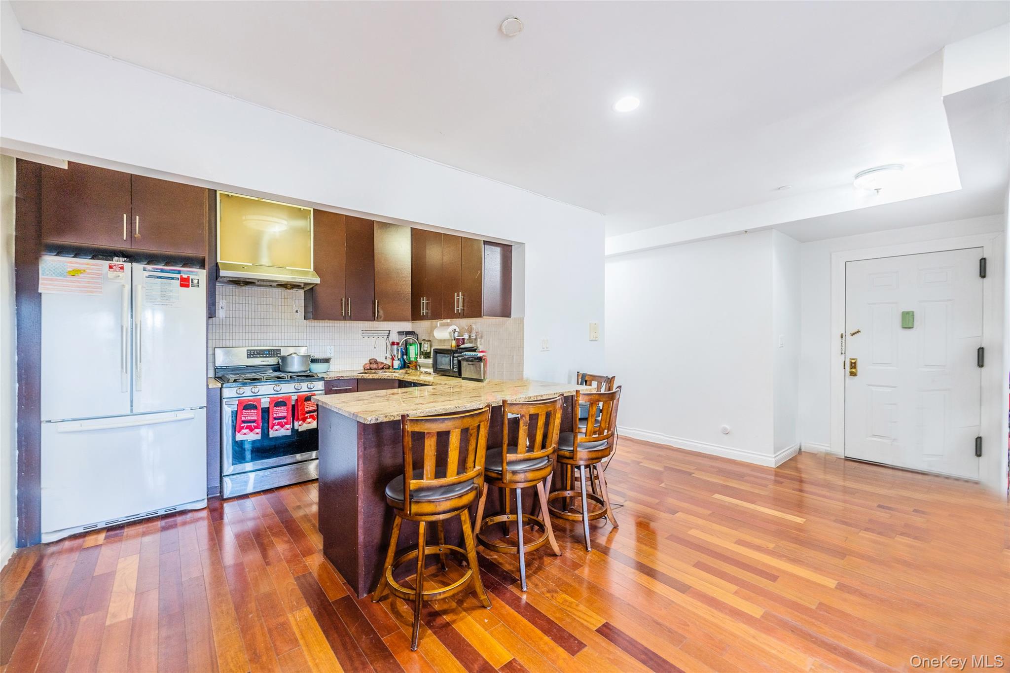 71-19 162nd Street, Unit 3D Queens, NY 11365 - Photo 7 of 14 Kitchen featuring a peninsula, freestanding refrigerator, stainless steel gas range, range hood, and a breakfast bar area