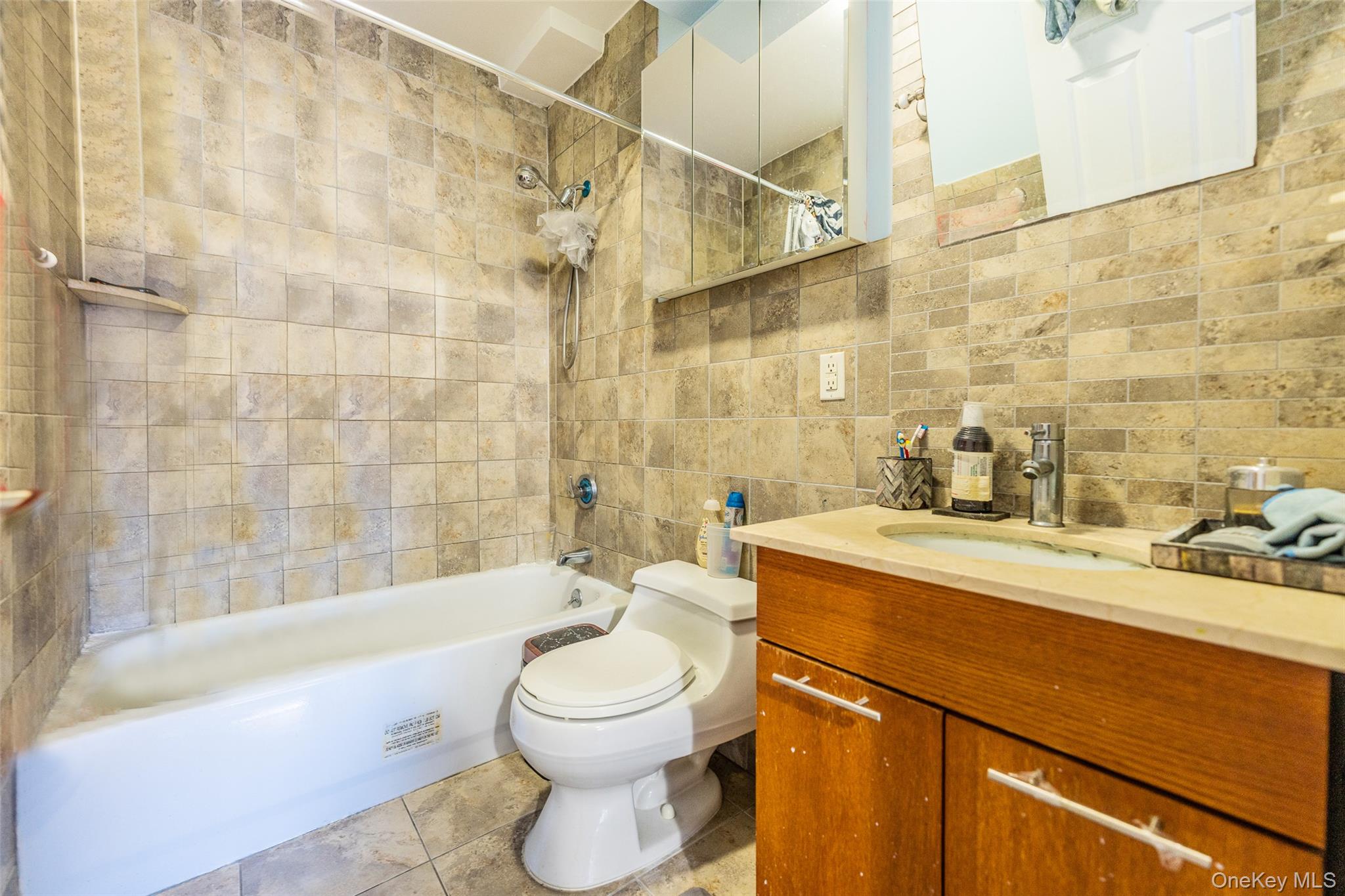 71-19 162nd Street, Unit 3D Queens, NY 11365 - Photo 9 of 14 Bathroom with tile walls, bathtub / shower combination, vanity, and light tile patterned flooring