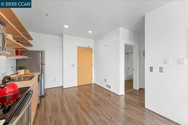 a view of a kitchen with a fridge and wooden floor