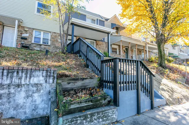 a view of a house with wooden fence next to a yard