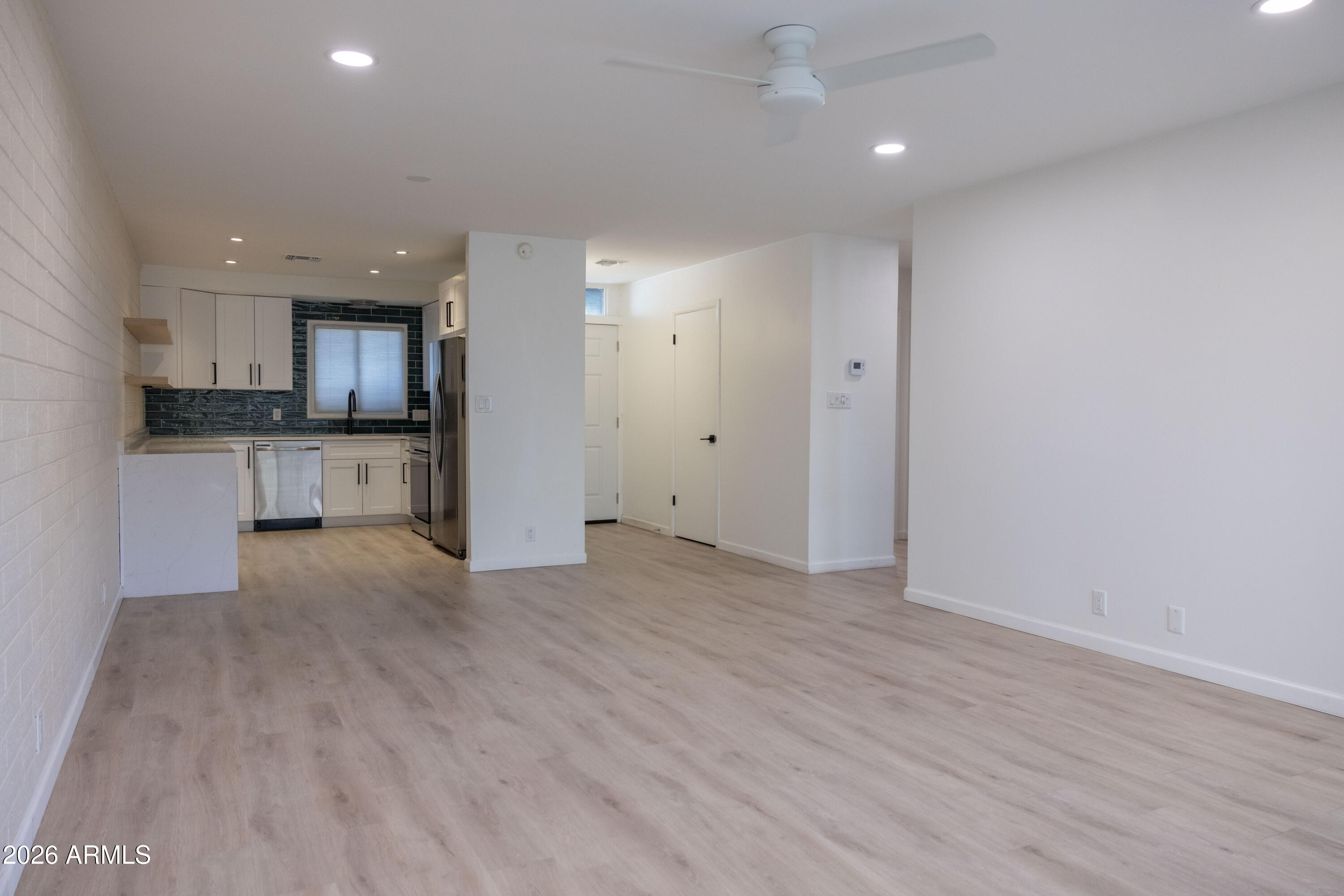 1450 East Bethany Home Road, Unit 31 Phoenix, AZ 85014 - Photo 6 of 24 an empty room with wooden floor and a kitchen