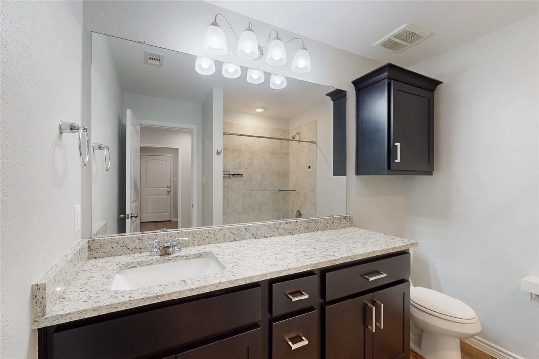 2029 Rock Rdg Avenue Bryan, TX 77807 - Photo 13 of 31 a bathroom with a granite countertop sink a toilet and mirror