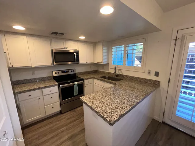 a kitchen with kitchen island granite countertop a stove sink and microwave