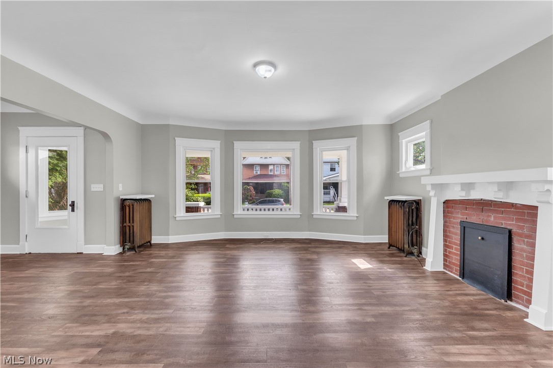 3506 Riverside Avenue Cleveland, OH 44109 - Photo 6 of 31 Open-concept living space featuring wood-finish flooring, a brick fireplace with a white mantel, and a bay window