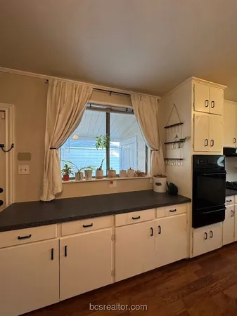 a kitchen with granite countertop white cabinets and white appliances