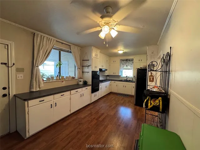 a large kitchen with cabinets wooden floor and stainless steel appliances
