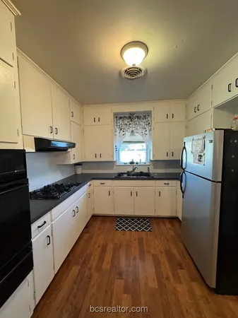 a kitchen with granite countertop a refrigerator and a stove top oven