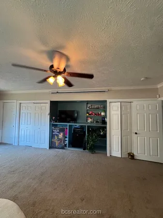 a view of n empty room with a ceiling fan and window