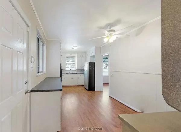 a view of a kitchen with a refrigerator a ceiling fan and wooden floor