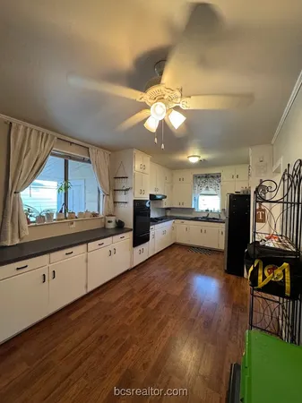 a large kitchen with cabinets wooden floor and stainless steel appliances