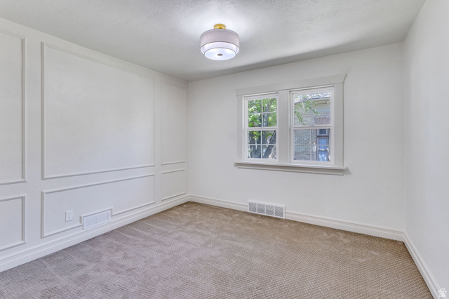 226 North 300 West Provo, UT 84601 - Photo 7 of 14 Room featuring a textured carpet, decorative wall paneling, and a contemporary flush mount light fixture