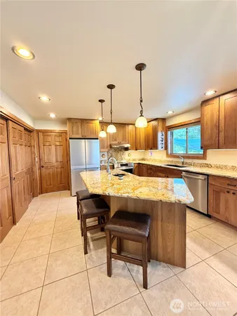 a view of a kitchen with kitchen island stainless steel appliances kitchen island granite countertop a sink and cabinets