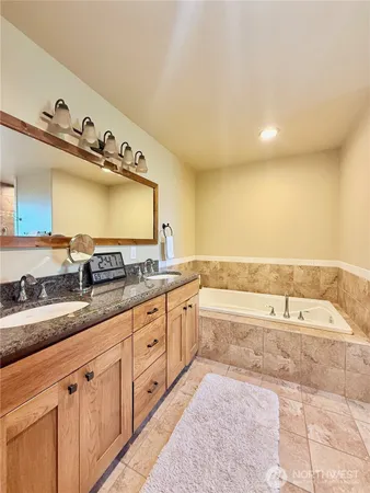 a spacious bathroom with a granite countertop sink and a bathtub
