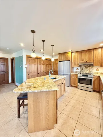 a view of a kitchen with kitchen island stainless steel appliances kitchen island granite countertop a sink and cabinets