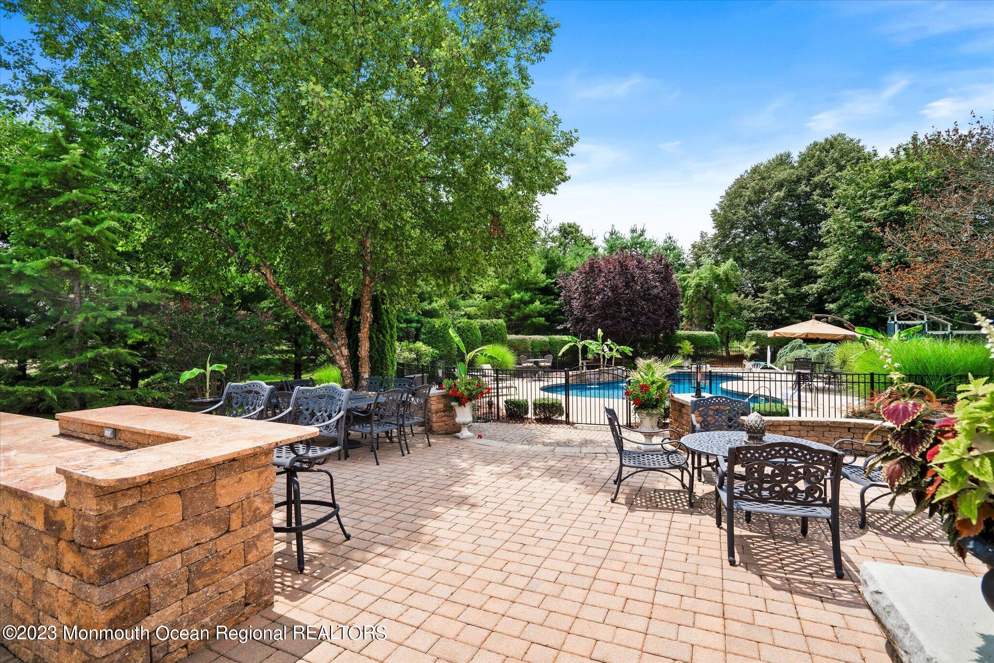27 Millennium Drive Columbus, NJ 08022 - Photo 60 of 82 a view of a patio with a dining table and chairs under an umbrella with large trees