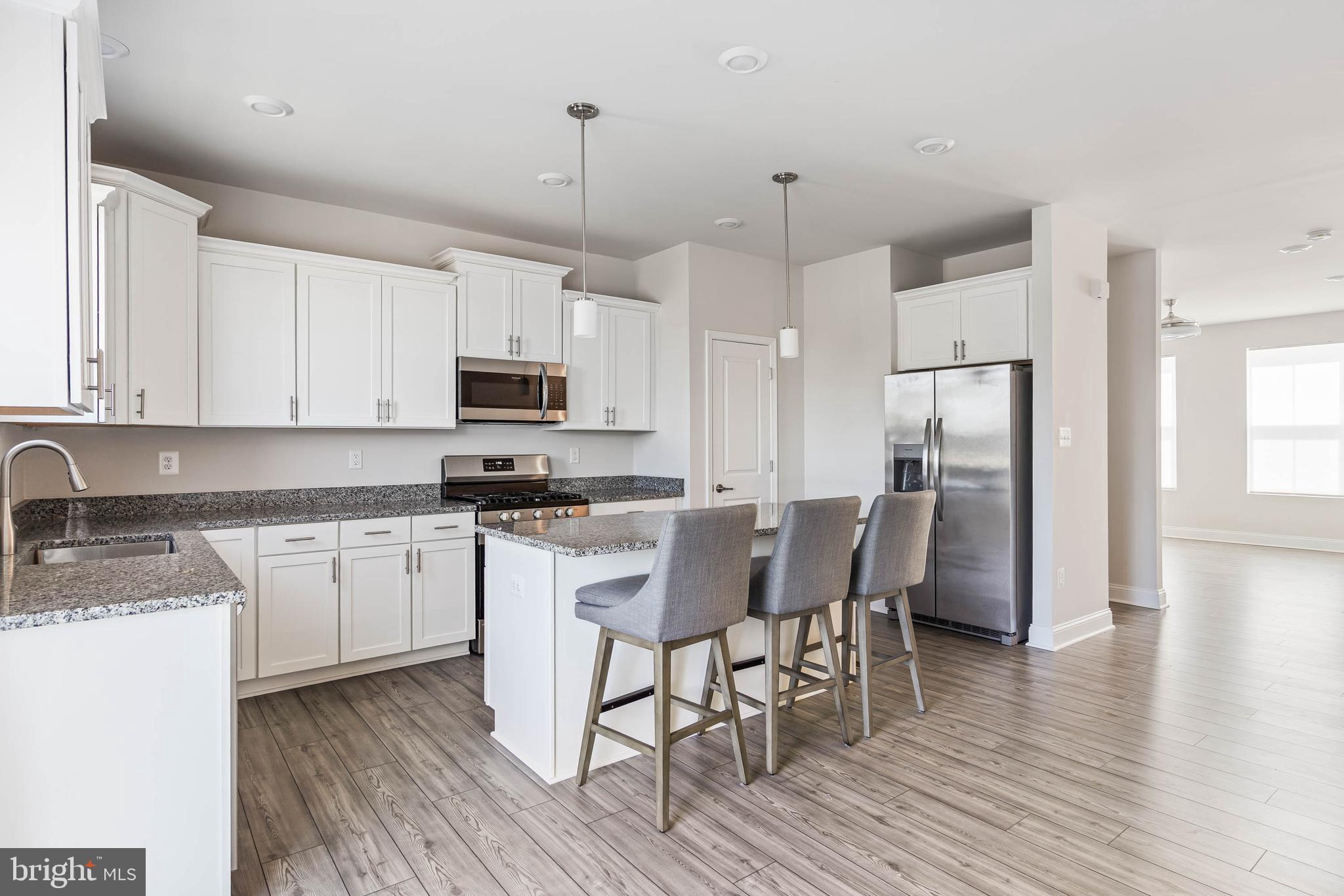 35303 Wright Way Millsboro, DE 19966 - Photo 8 of 26 a kitchen with stainless steel appliances granite countertop a table chairs microwave and sink
