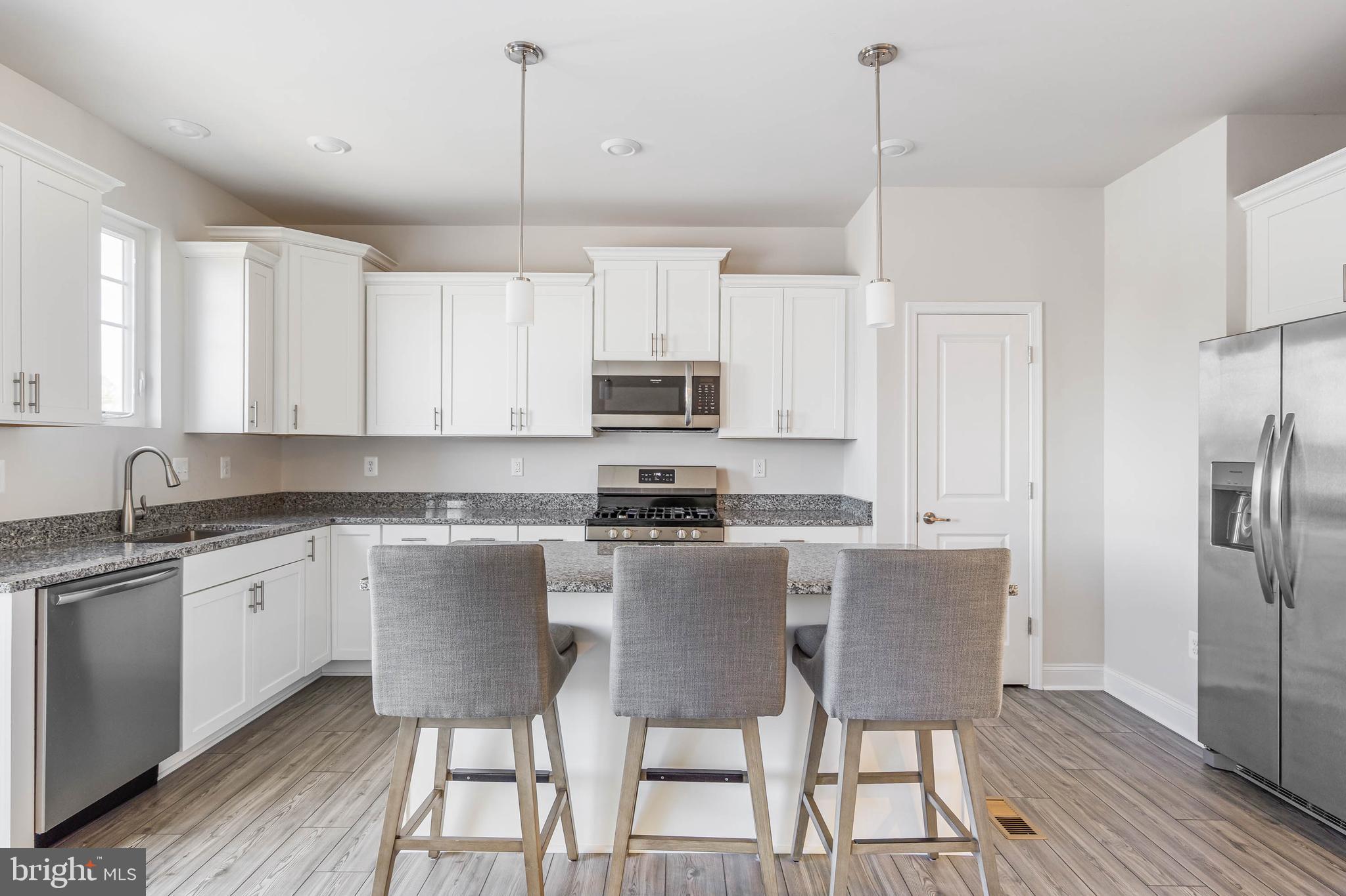 35303 Wright Way Millsboro, DE 19966 - Photo 9 of 26 a kitchen with stainless steel appliances granite countertop a stove a sink dishwasher a refrigerator and a dining table with wooden floor